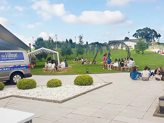 Giovani che parlano con i loro coach internazionali nei giardini del campo estivo inglese the Village