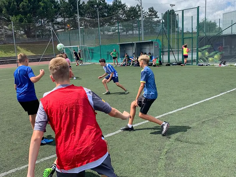 Gruppo di giovani che si allenano a calcio con coach internazionali al campo estivo in Spagna